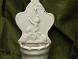 a white vase with a statue on it on a green cloth