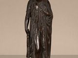 une statue antique en bronze représentant une femme tenant un panier