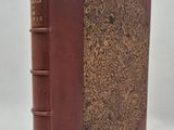 an old book with a brown cover sitting on top of a white surface