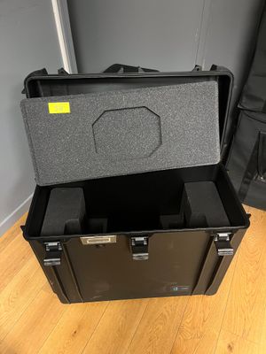 une valise noire posée sur un parquet, à côté d'une autre valise