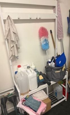 a closet with a shelf and a rack with cleaning supplies