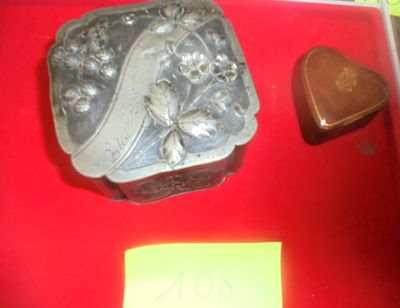 une boîte en argent sur laquelle figure le portrait d'une femme, posée sur une table rouge