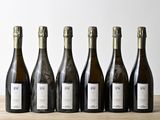 six bottles of wine are lined up on a wooden table
