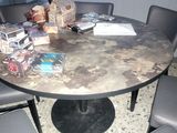 a round table with chairs around it and a vase on top of it