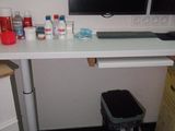 a computer desk with two monitors and a trash can