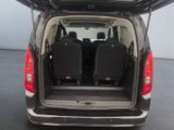the back of a black van with its doors open and luggage in the trunk