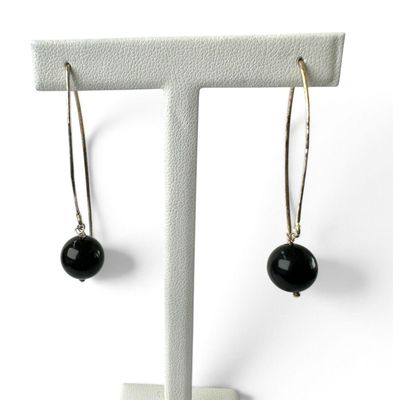 une paire de boucles d'oreilles ornées de perles noires, suspendues à un support blanc