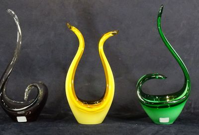 trois vases en verre de couleurs différentes posés les uns à côté des autres sur une surface noire