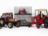 Plusieurs tracteurs miniatures sont alignés les uns à côté des autres sur une surface blanche