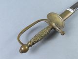 a gold colored sword with a metal handle on a gray surface