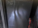 a black refrigerator sitting inside of a room next to a wall