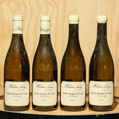 quatre bouteilles de vin sont alignées sur un plateau en bois