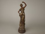 une statue en bronze représentant une femme tenant une balle dans la main
