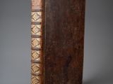 un vieux livre avec une couverture en cuir marron sur fond gris