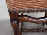 a close up of a wooden chair with a striped upholstered seat