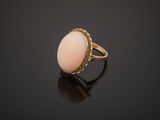 a gold ring with a pink stone on a black surface