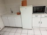 une petite cuisine avec un réfrigérateur blanc et des placards blancs