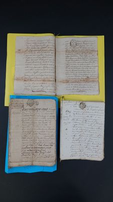 trois feuilles de papier usagé, couvertes d'écriture, posées sur une table