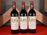 three bottles of red wine sit on a table next to a wooden crate