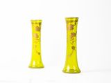 une paire de vases jaunes ornés de fleurs dorées sur fond blanc