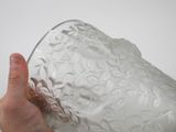 a person holding a clear glass vase in their hand