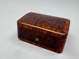 a small wooden box with a metal handle on a white surface