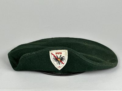 un béret vert orné d'un écusson blanc sur lequel figure une étoile