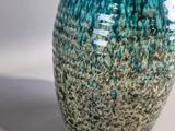 a blue and green vase sitting on a white surface
