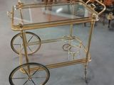 un chariot à boissons doré avec un plateau en verre, posé au sol
