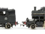 two black trains sitting side by side on a white surface