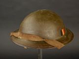 an old helmet with a ribbon on a stand against a black background