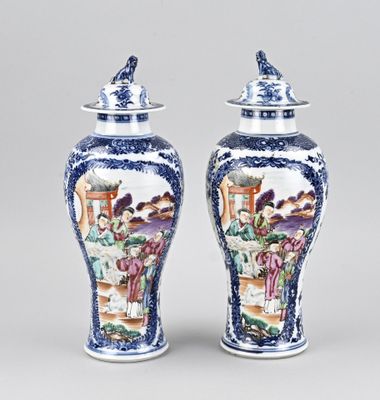 pair of blue and white vases with figures on them sitting on a table