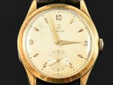 a close up of a gold wrist watch on a black surface