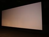 un écran de projection dans l'obscurité, devant lequel se tient une personne
