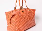 an orange goyard bag sitting on top of a white surface
