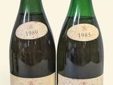 two bottles of wine sitting next to each other on a white surface