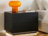 a black night stand with a yellow lamp on top of it