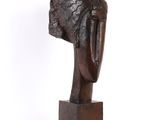 une photo d'une sculpture représentant une tête posée sur un socle en bois
