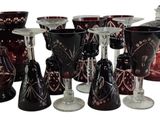 many different colored glass vases and wine glasses on the table
