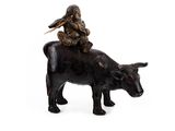 figurine représentant un homme chevauchant une vache, avec un oiseau sur le dos