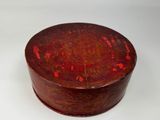 an old wooden box with red paint on it sitting on a white surface