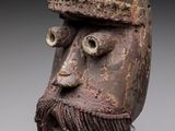un gros plan d'un masque en bois barbu posé sur un socle