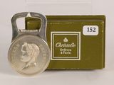 a bottle opener with a coin on it next to a box of cigarettes
