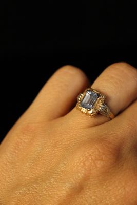a woman ' s hand holding a ring with a diamond on it