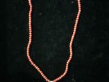 un collier de perles rouges orné d'une croix