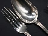 a silver spoon and a fork on a black table