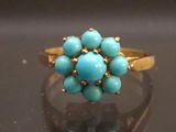 an image of a gold ring with turquoise stones on a black surface