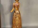 a wooden statue of a woman with a hat and a dog