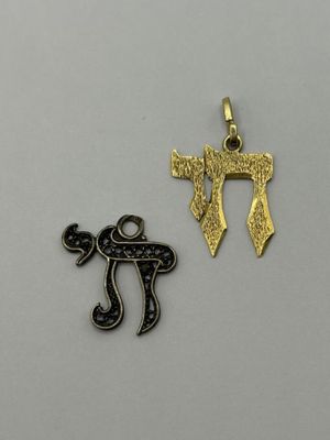 two gold and silver charms with hebrew symbols on them