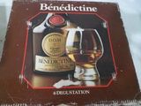 une photo d'un flacon de Bénédicine à côté d'un verre de vin